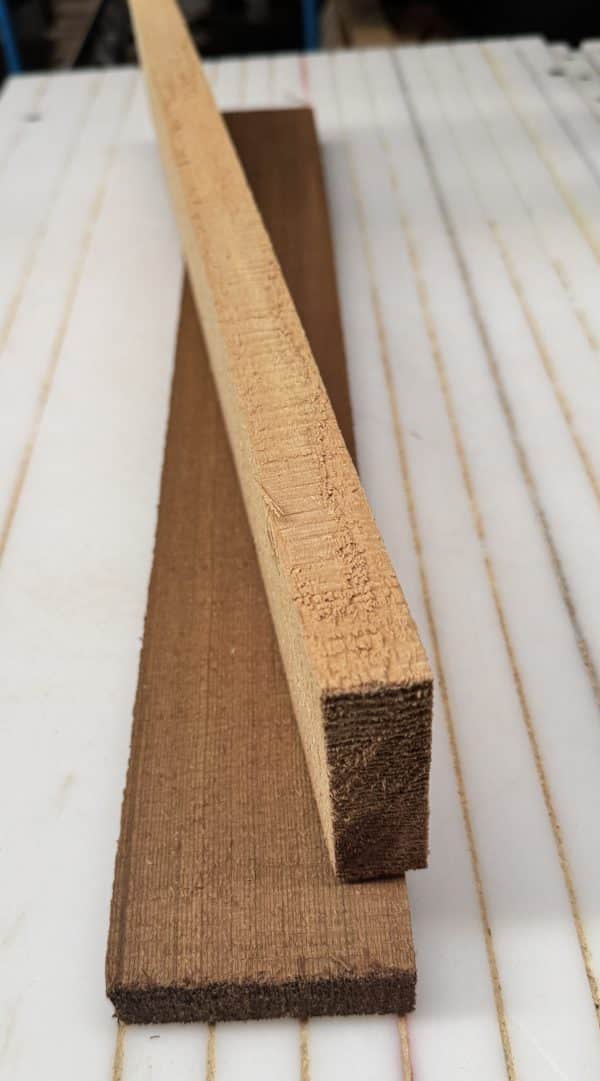 A light-colored, square piece of unfinished Western Red Cedar bracewood on a darker wood board.