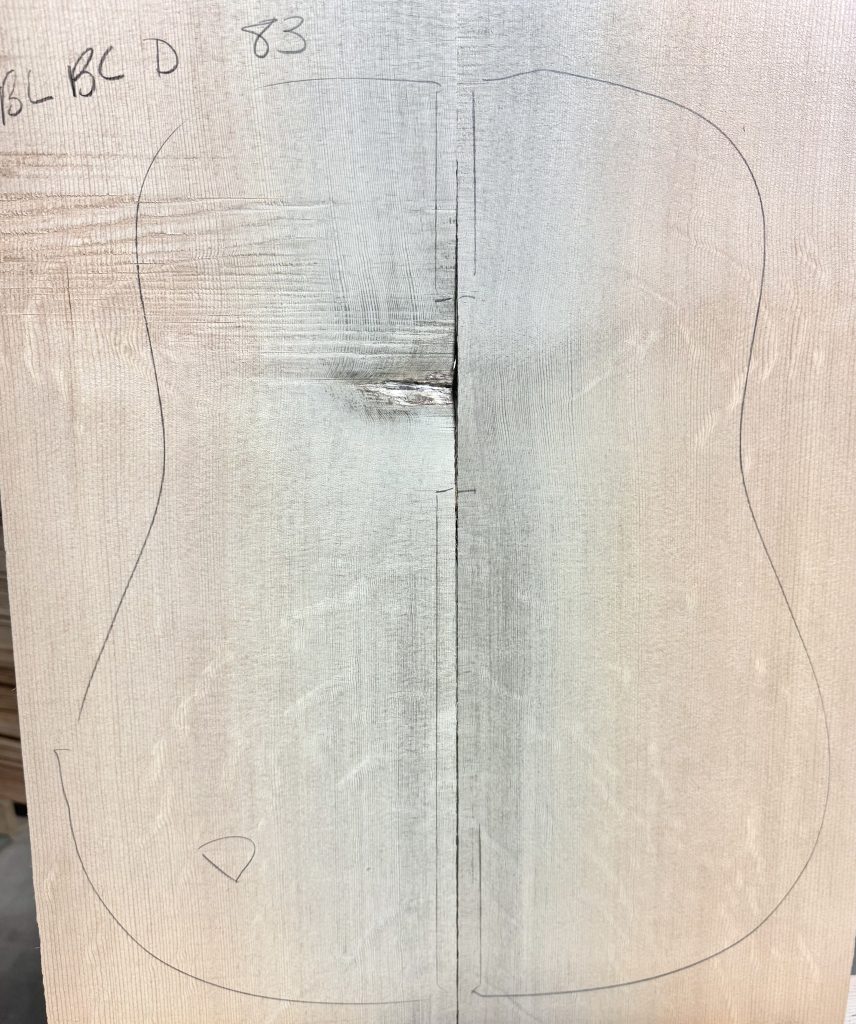 Two joined light wood pieces with a guitar body outline and identifying marks, showcasing prospective Blue Bearclaw Guitar Tops.